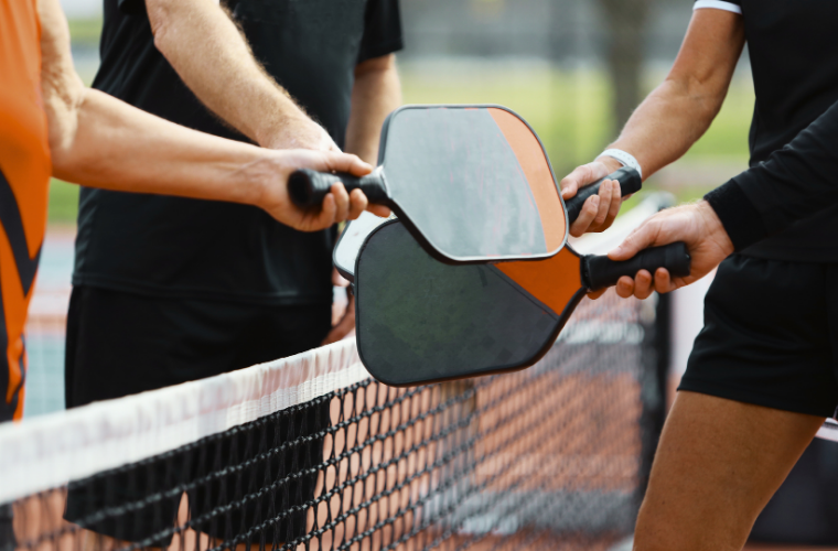 Pickleball players bumping paddles after a match Pickleball players bumping paddles after a match